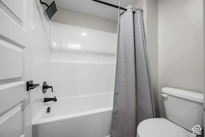 White bathtub with matte black fixtures and a rain shower head