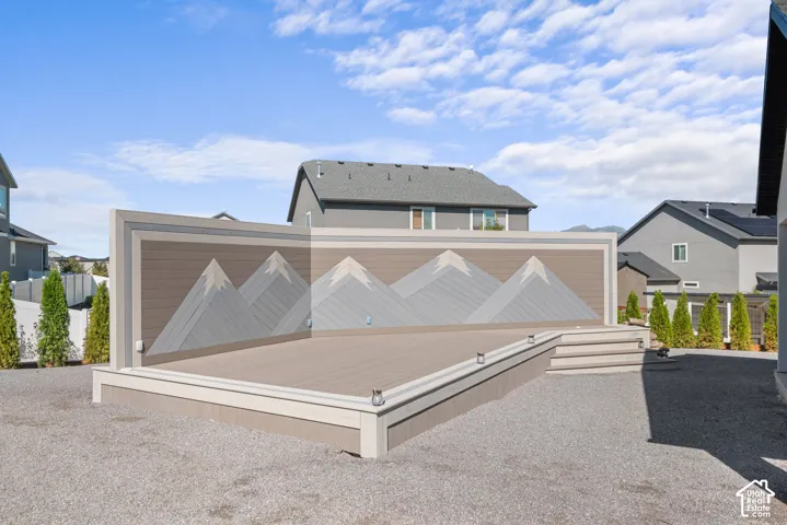 Expansive outdoor deck featuring wood-finish flooring and a decorative mountain-themed privacy wall