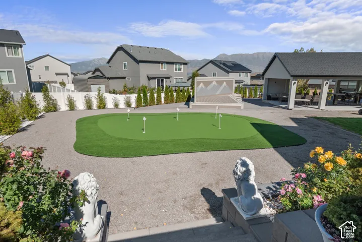 Spacious backyard featuring a putting green, covered patio structure, and a secondary patio area with a privacy screen