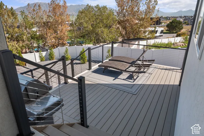 Spacious outdoor deck featuring light-toned composite decking, contemporary cable railings, and a solid privacy wall