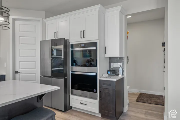 White shaker cabinetry with black hardware, stainless steel double wall oven, and built-in refrigerator