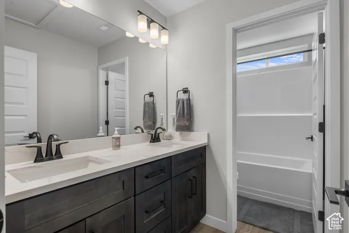 Dual undermount sinks with matte black fixtures, spacious vanity with stone countertops, and dark wood-finish cabinetry