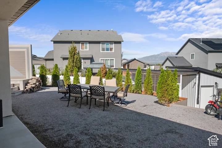 Expansive gravel patio area with mature evergreen plantings and a mountain backdrop