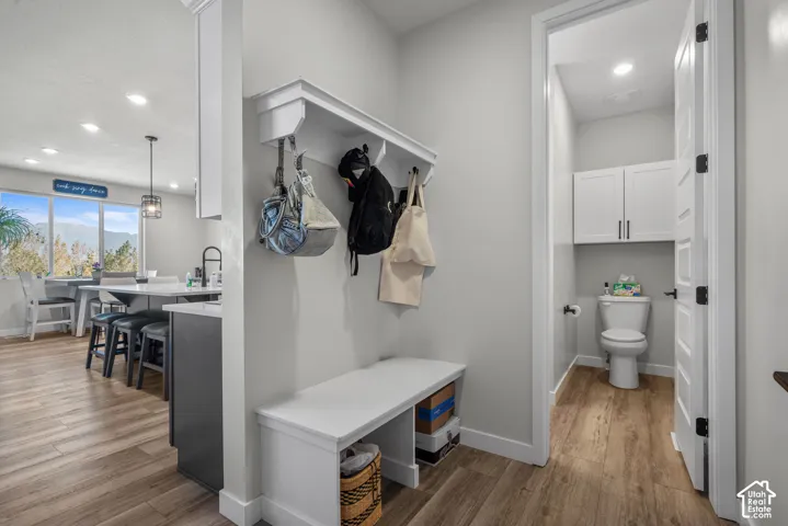 Wood-finish flooring throughout, a built-in hall tree with seating, and a half bath with storage cabinetry