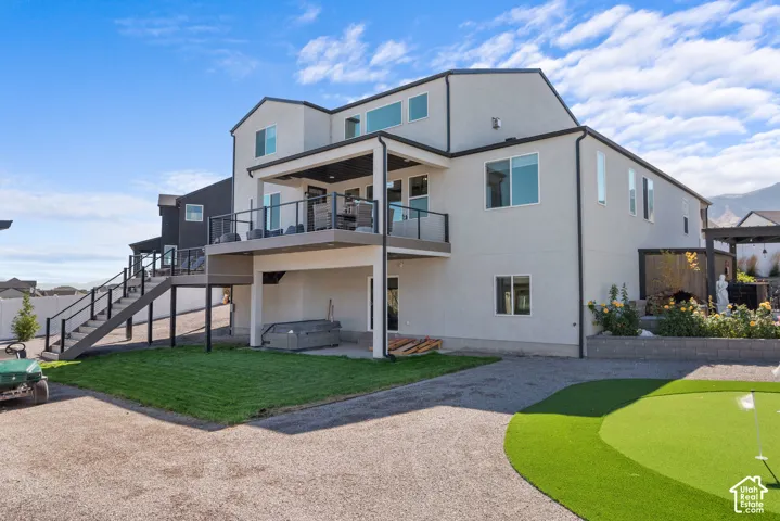 Multi-level exterior with a raised deck, glass railings, and a lower patio area