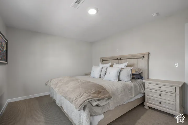 Carpeted room featuring a light-colored wood headboard with barn door detailing, recessed ceiling light, and a matching wood nightstand with three drawers