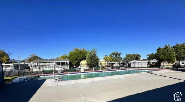 Outdoor swimming pool featuring a concrete deck and perimeter fencing.