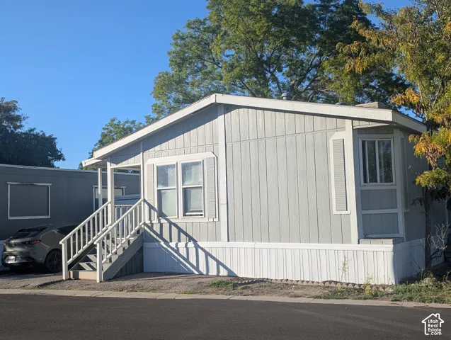 Light gray siding exterior with white trim, featuring a front entry staircase and an angled bay window.