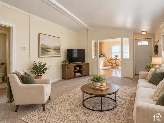 Carpeted living area with light-toned walls, decorative crown molding, and a built-in media console