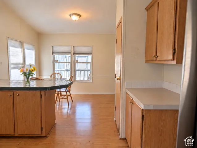 Kitchen featuring wood-finish cabinetry, tile countertop island, and wood-finish flooring