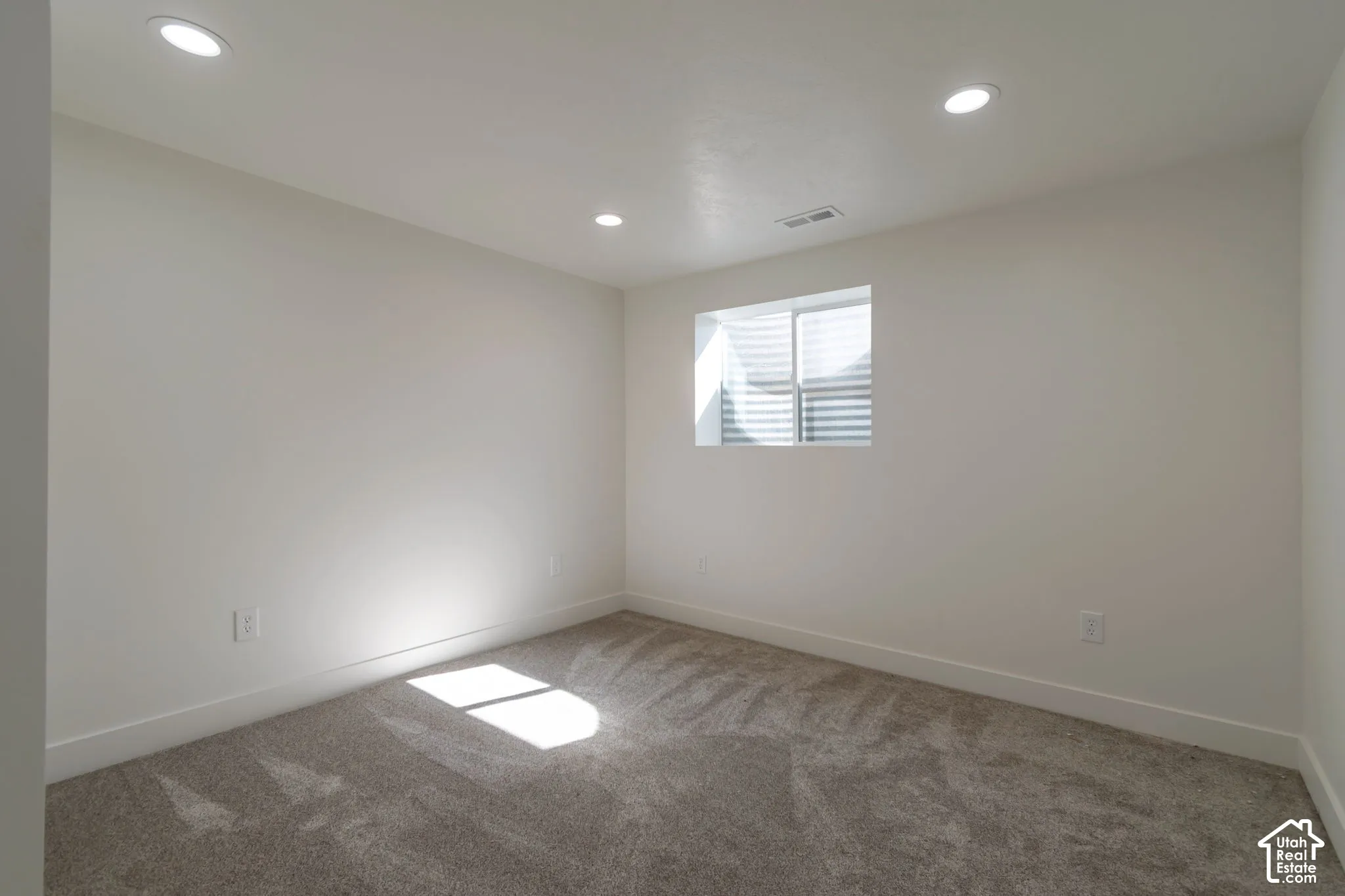 Recessed ceiling lighting, a window with blinds, light-colored walls, and carpeting