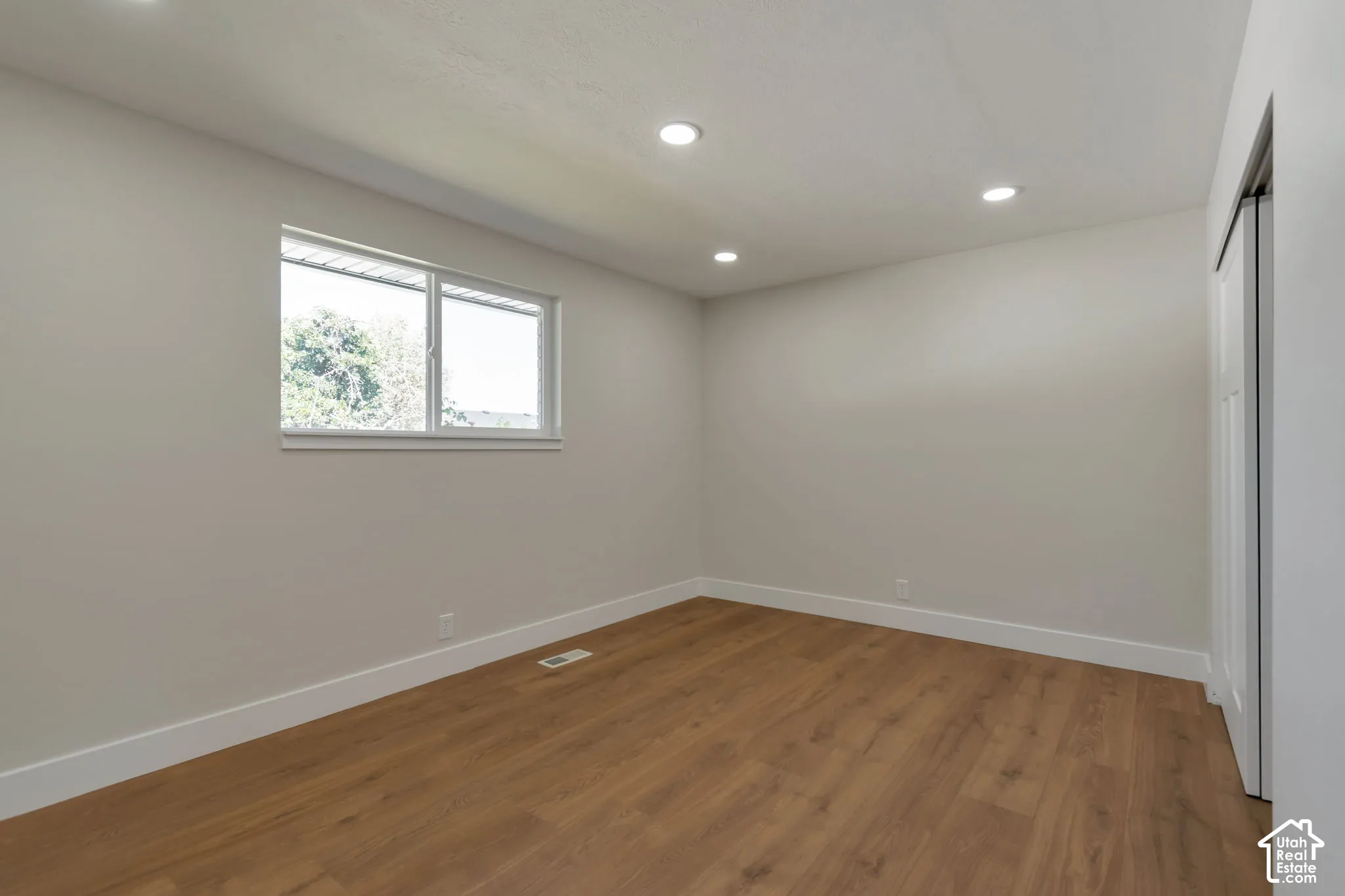 Recessed lighting, wood-finish flooring, and white trim