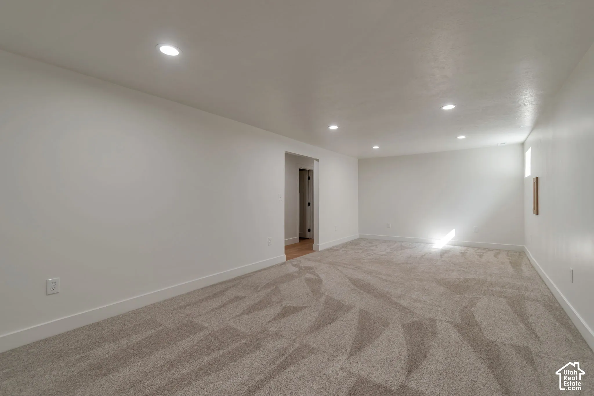 Recessed lighting, light-colored walls, patterned carpet flooring, and a single window