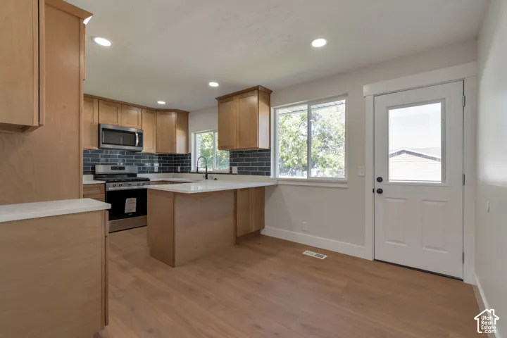 Kitchen featuring wood-finish flooring, recessed lighting, and light wood cabinetry with stainless steel appliances