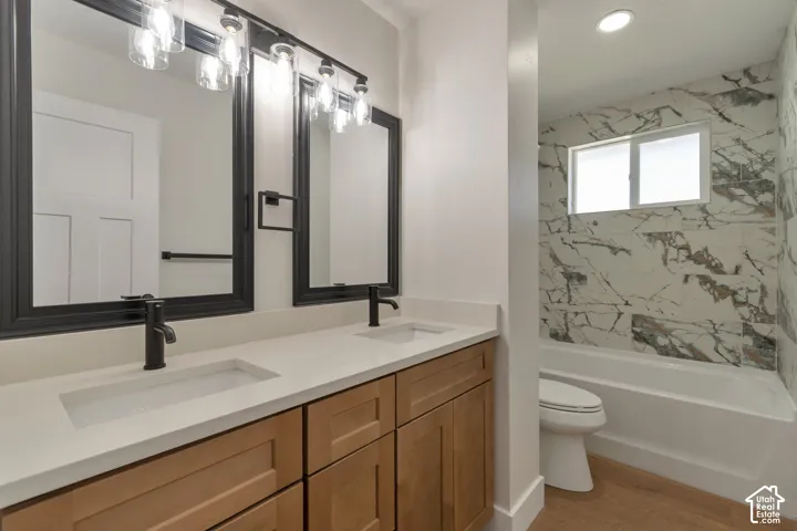 Dual vanity with light wood-finish cabinetry, integrated sinks, and matte black fixtures