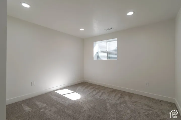 Recessed ceiling lighting, a window with blinds, light-colored walls, and carpeting
