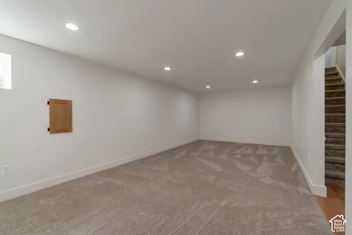 Recessed lighting illuminates the carpeted flooring and white walls