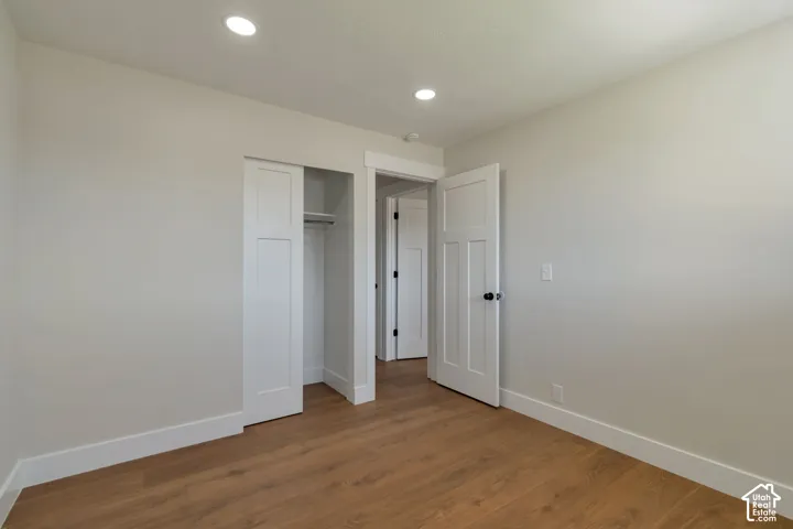 Recessed ceiling lighting, durable wood-finish flooring, white trim, white paneled doors, and a built-in closet with sliding doors