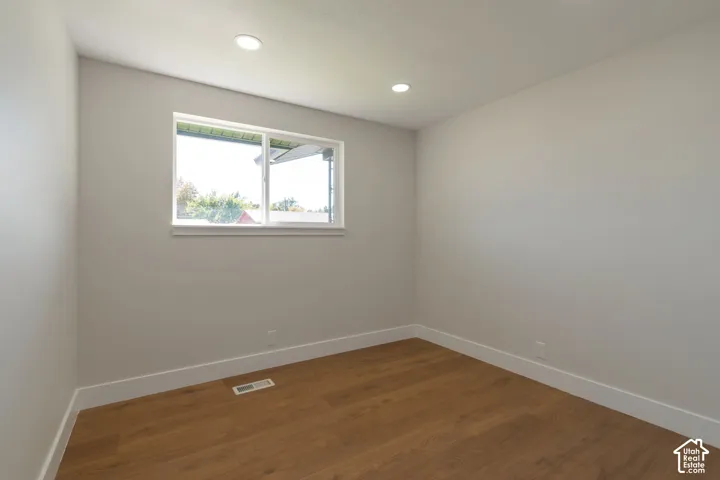 Recessed lighting, wood-finish flooring, white trim, and a window