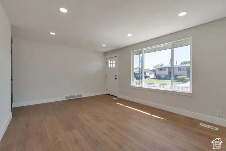 Recessed ceiling lighting, wood-finish flooring, white trim, and a white entry door with glass inserts