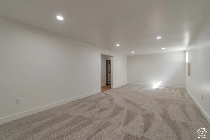 Recessed lighting, light-colored walls, patterned carpet flooring, and a single window