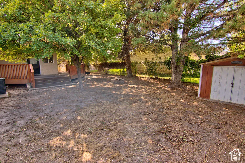 Spacious yard featuring mature trees, a multi-level wood deck, and a detached storage shed