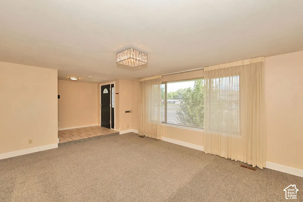 Wall-to-wall carpeting, large picture window, flush mount lighting, tiled entryway, and a paneled front door