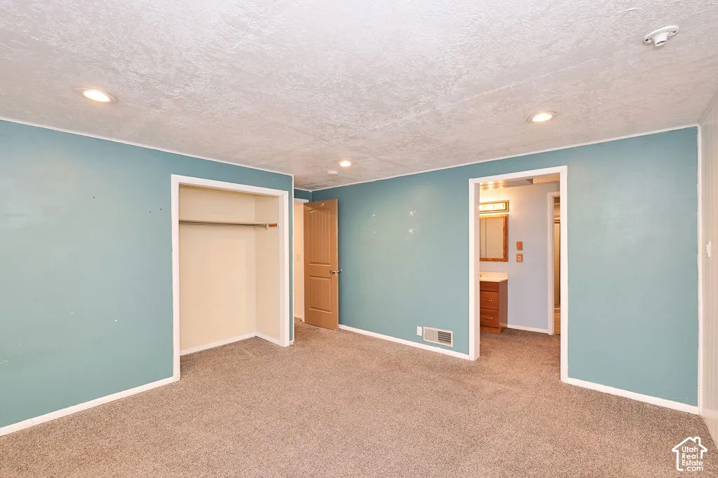 Recessed lighting illuminates the room, featuring a built-in closet with a hanging rod