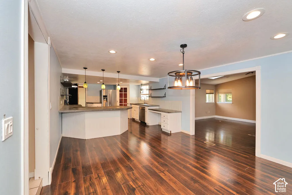 Wood-finish flooring throughout, kitchen with counter seating, stainless steel appliances, recessed lighting, and a contemporary chandelier