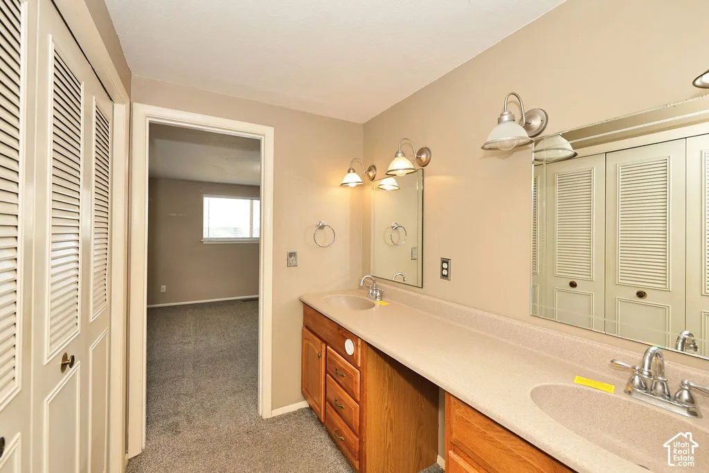 Dual vanity with integrated sinks, ample countertop space, wood-finish cabinetry, and overhead sconce lighting
