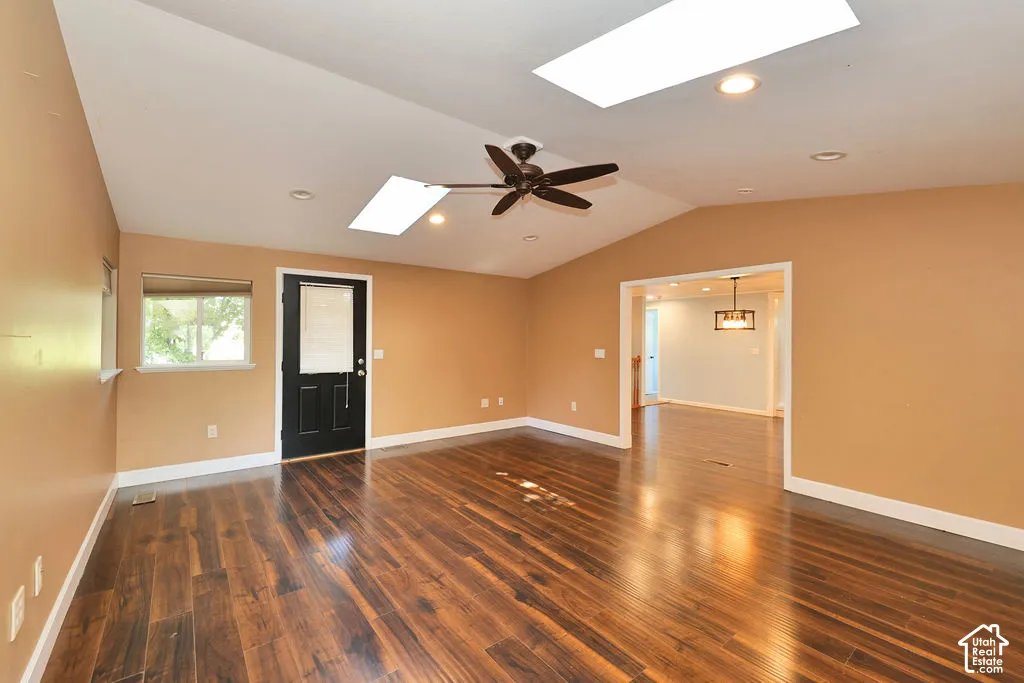 Vaulted ceiling with integrated skylights, rich wood-finish flooring, recessed lighting, and a ceiling fan