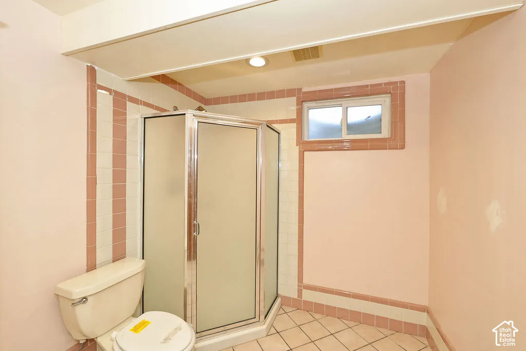 Walk-in shower with frosted glass enclosure, tile walls, and a tiled floor
