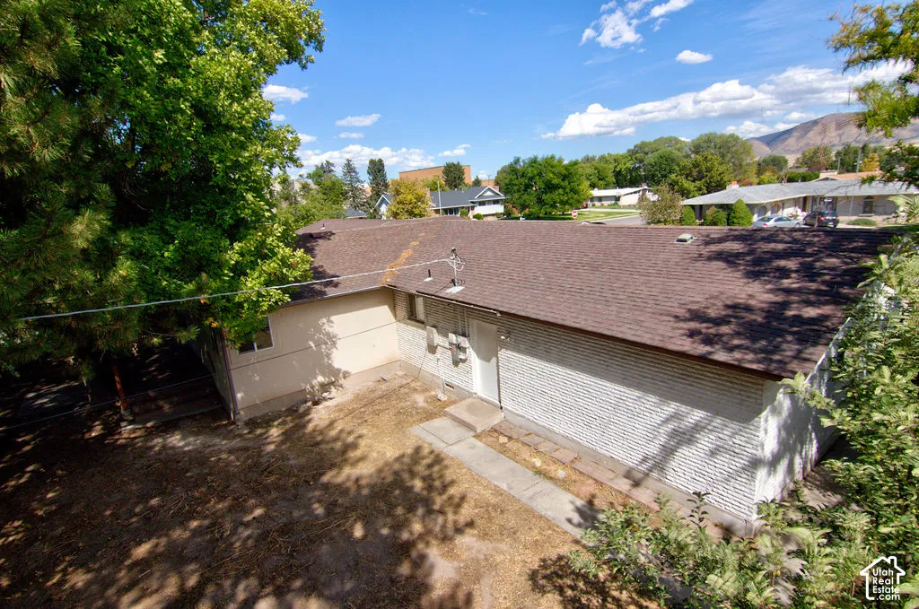 Brown shingle roof, white painted brick exterior, and light-colored stucco elements