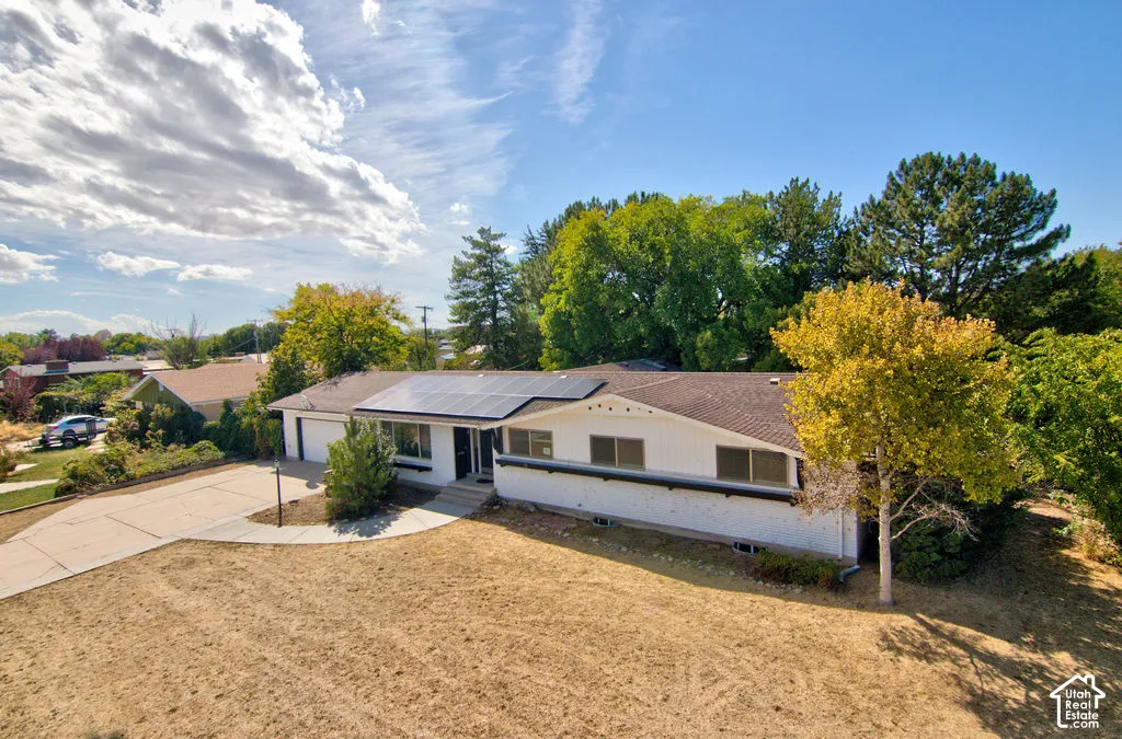 Single-story residence featuring a shingled roof, solar panels, and an attached two-car garage