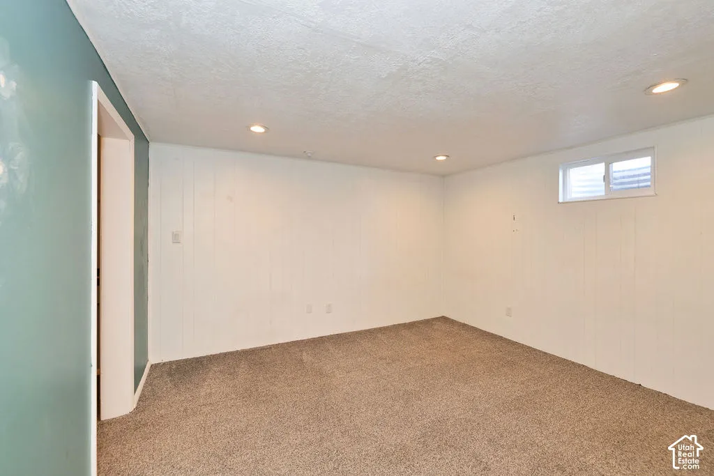 Recessed ceiling lighting, textured ceiling finish, light-toned wall paneling, carpet flooring, and a single window