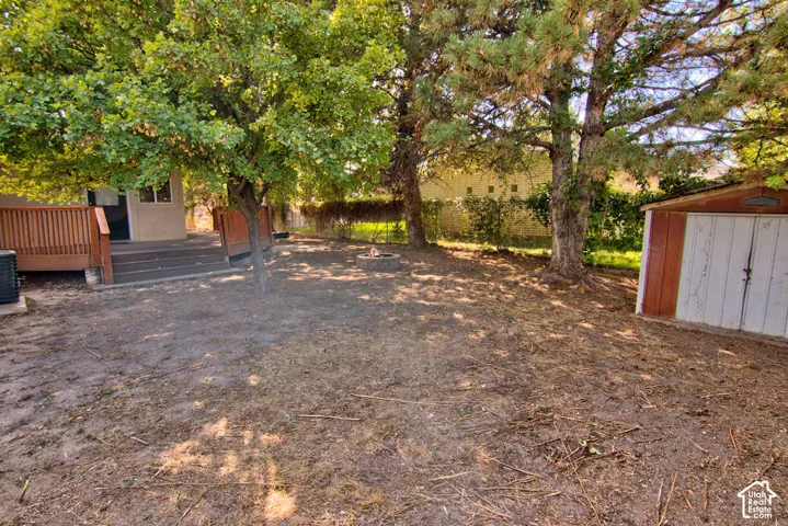 Spacious yard featuring mature trees, a multi-level wood deck, and a detached storage shed