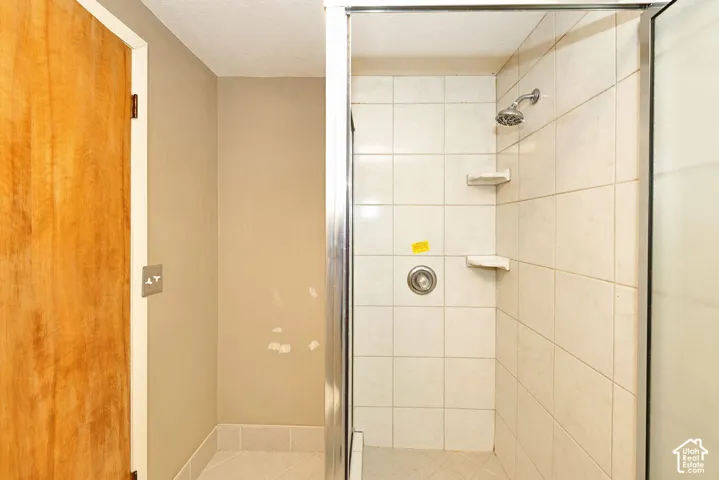 Tiled shower enclosure with a chrome shower head and built-in shelving