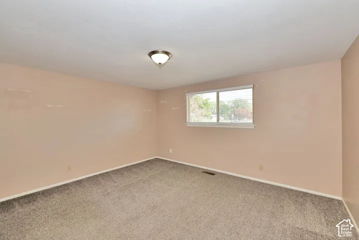 Recessed window with blinds, wall-mounted ceiling light fixture, and neutral carpeting