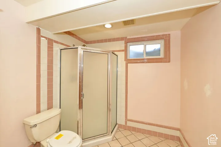 Walk-in shower with frosted glass enclosure, tile walls, and a tiled floor