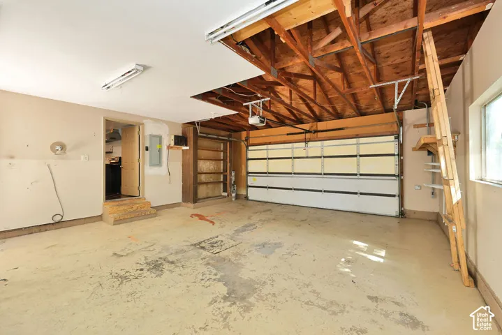 Attached garage with exposed wood ceiling beams, white garage door, and a window for natural light