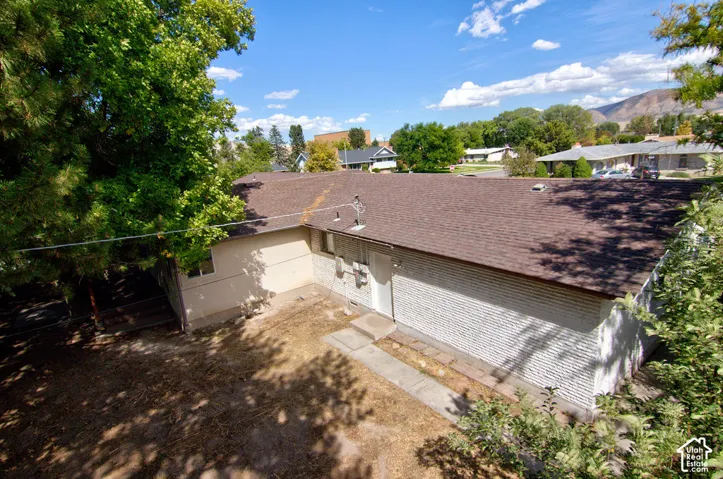 Brown shingle roof, white painted brick exterior, and light-colored stucco elements