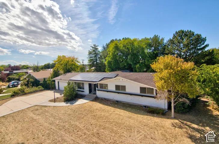Single-story residence featuring a shingled roof, solar panels, and an attached two-car garage