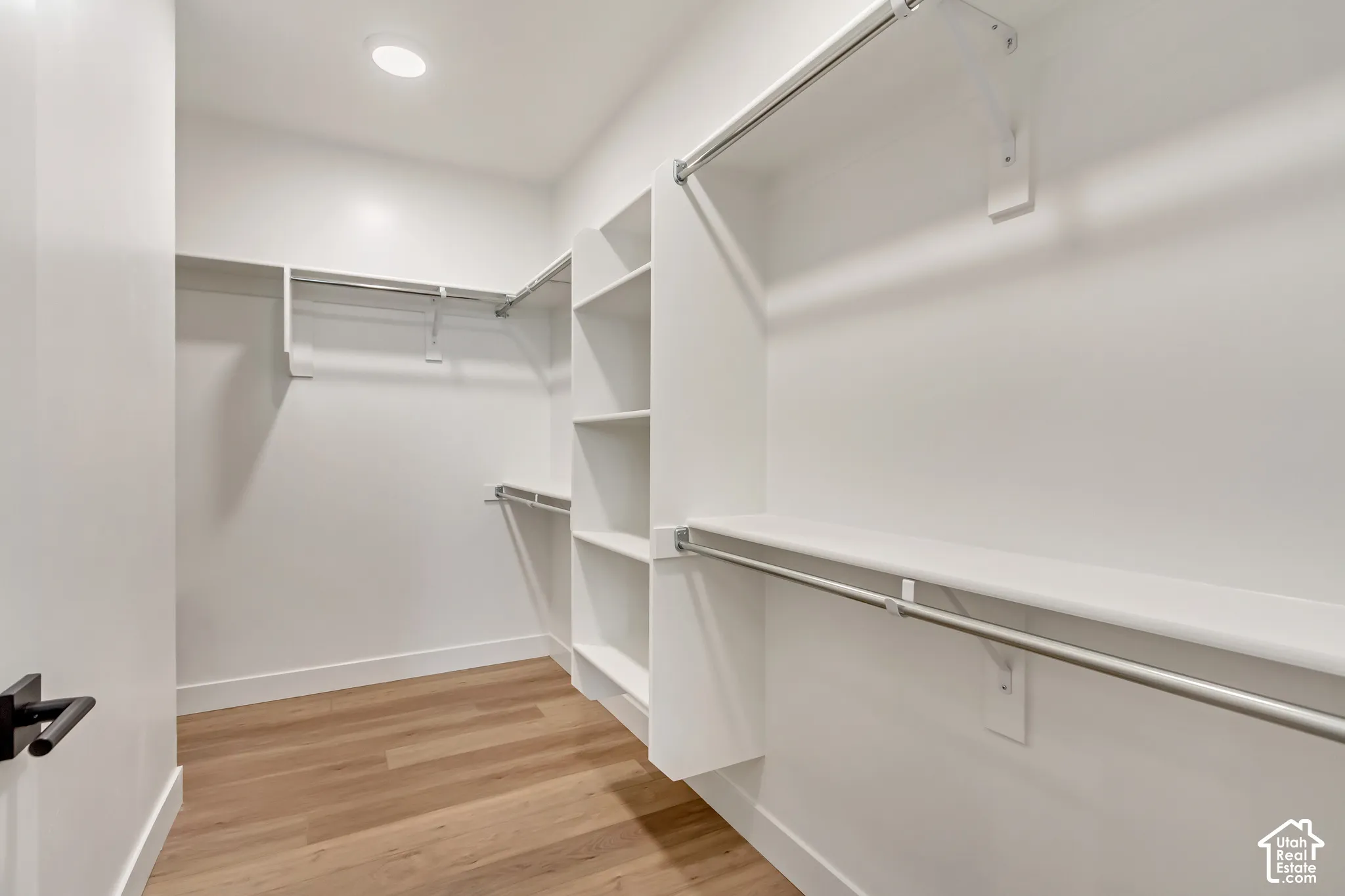 Walk-in closet featuring wood-finish flooring, recessed lighting, built-in shelving, and multiple hanging rods