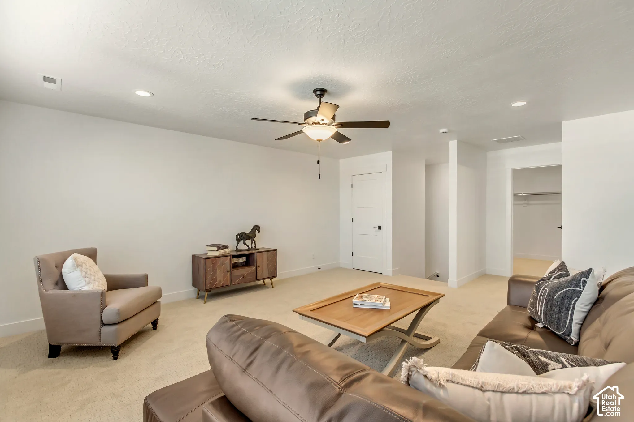 Recessed lighting, ceiling fan, white paneled doors with dark hardware, and light-colored carpeting