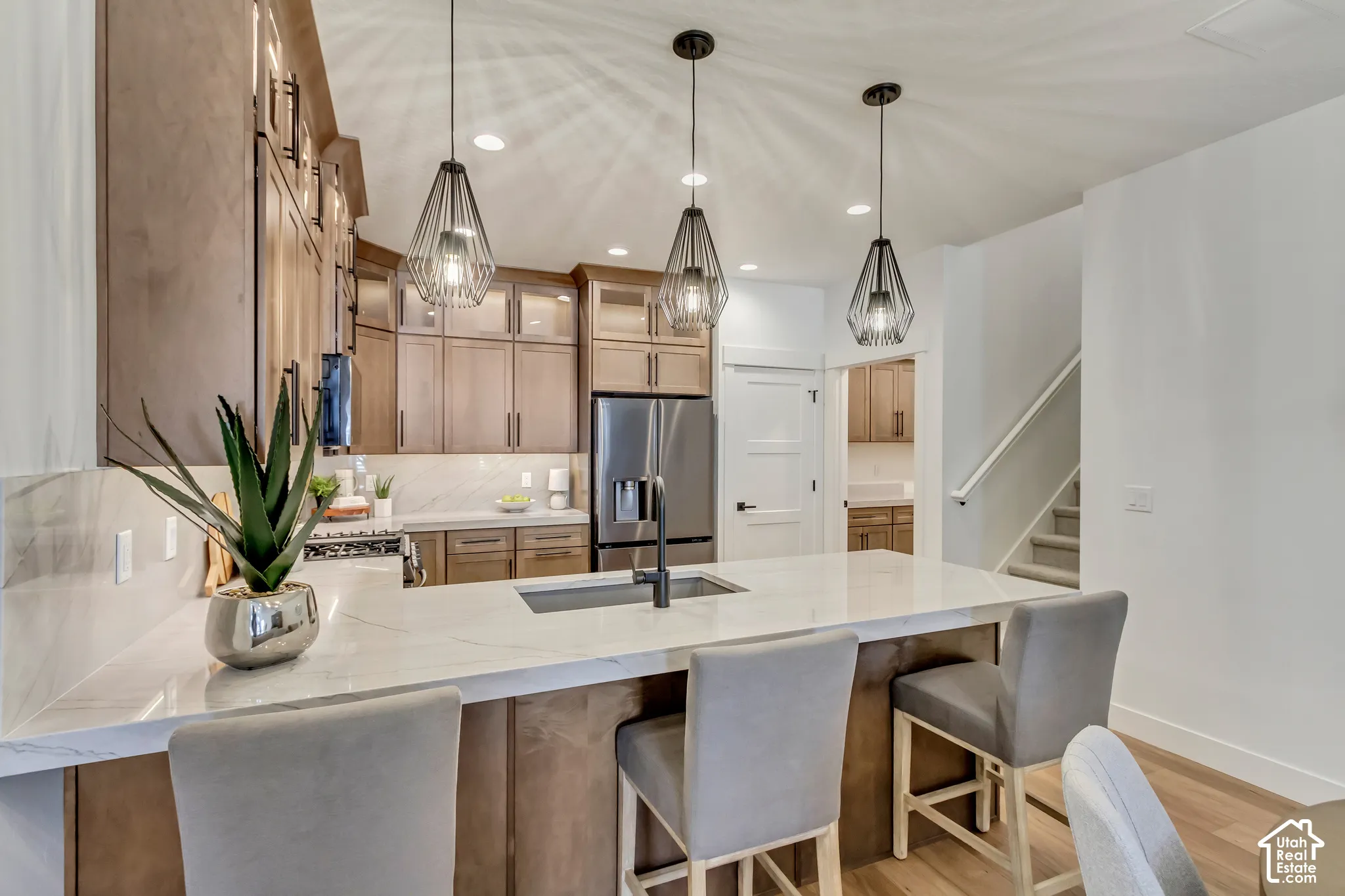 Gourmet kitchen with an expansive island, integrated sink, and three pendant light fixtures