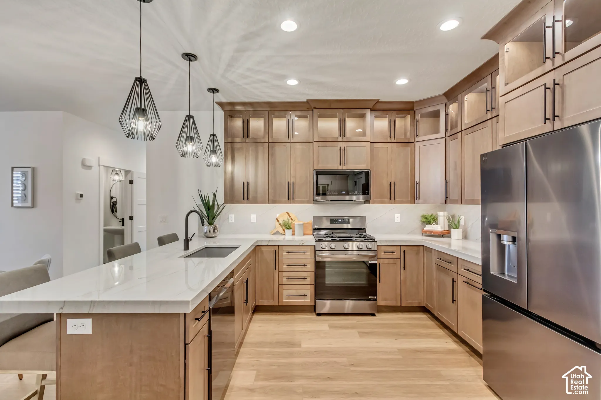 Modern kitchen featuring stainless steel appliances, light wood-finish cabinetry, a large center island with counter seating, and white countertops