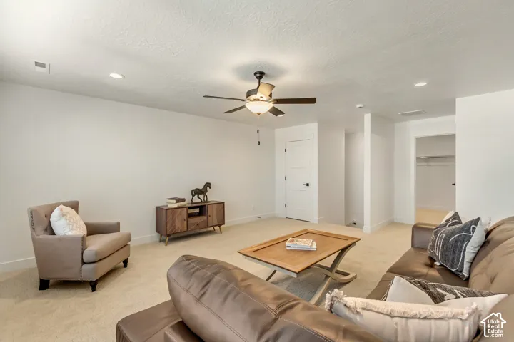 Recessed lighting, ceiling fan, white paneled doors with dark hardware, and light-colored carpeting