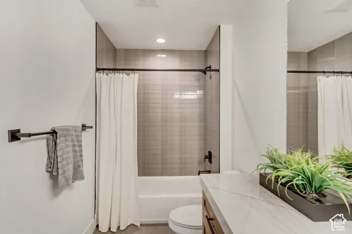 Tub/shower combination with subway tile surround, matte black fixtures, and a white vanity with a marble-finish countertop
