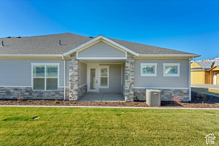 Light gray siding exterior with a covered entry, stone column accents, and a shingled roof