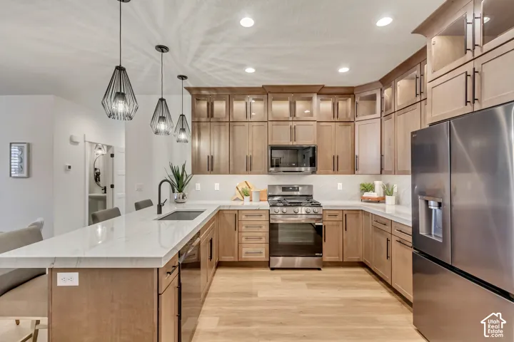 Modern kitchen featuring stainless steel appliances, light wood-finish cabinetry, a large center island with counter seating, and white countertops